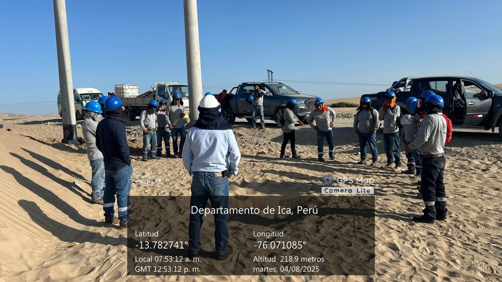 SECTORES Reunión de seguridad al pie de un poste de concreto con trabajadores con casco azul en el desierto