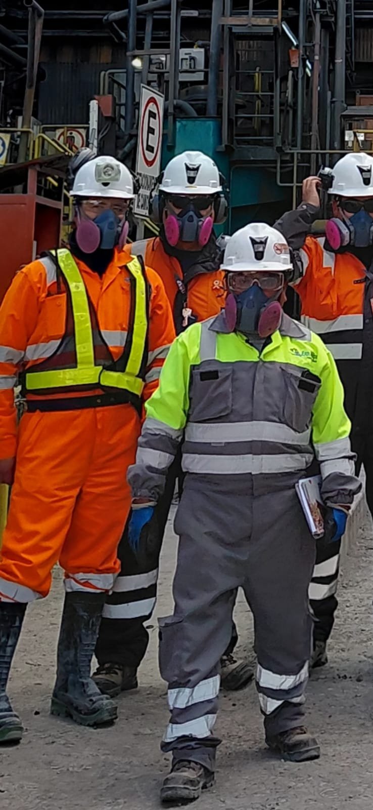 Equipo de trabajadores con respiradores, casco y ropa de alta visibilidad en una planta industrial